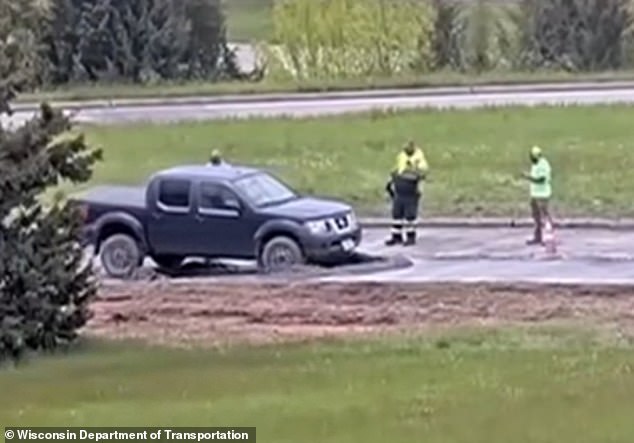 Wisconsin driver ignores road closure signs and drives into wet concrete.