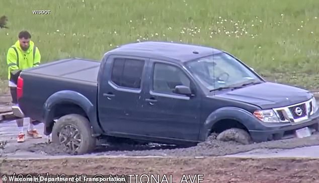 Wisconsin driver ignores road closure signs and drives into wet concrete.